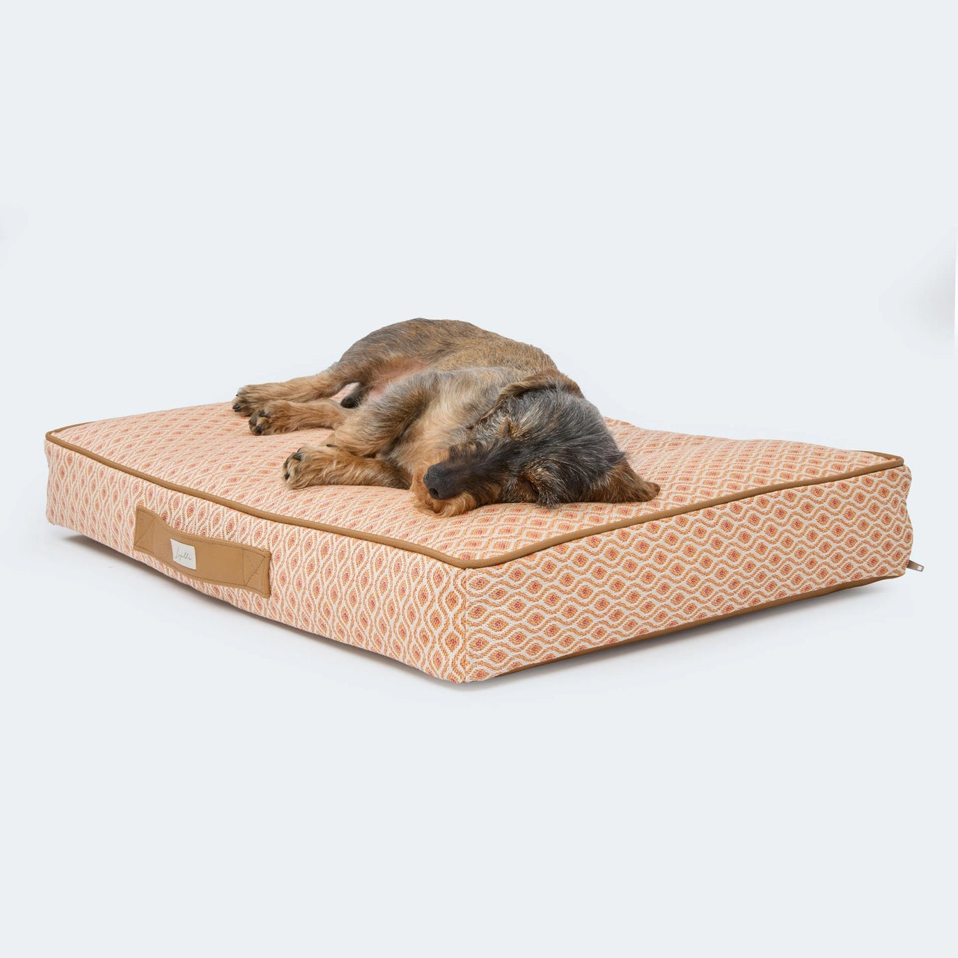 Hund liegt auf orthopädischem Hundekissen Santorini von Leopold's Finest in orange. Das Kissen ist Indoor und Outdoor geeignet.